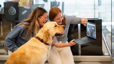 Zwei Frauen und ein Hund betachten einen Video-Chat im Laptop